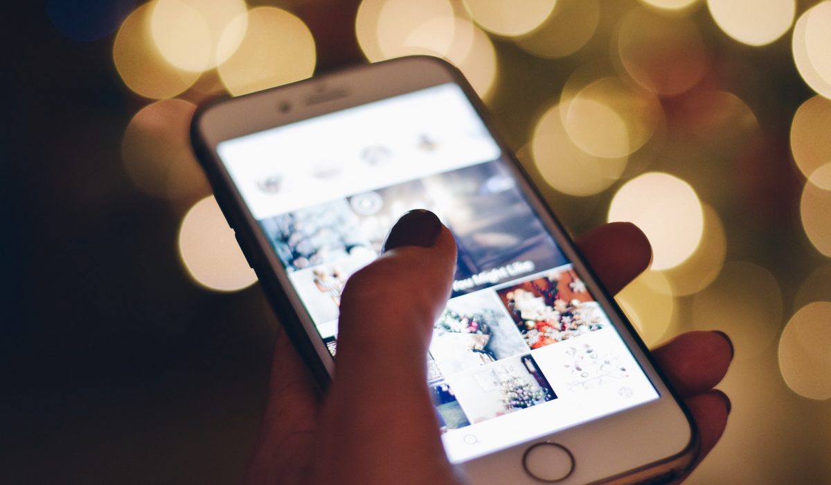 Mobile phone with Instagram social media images on the screen and bokeh lights in the background